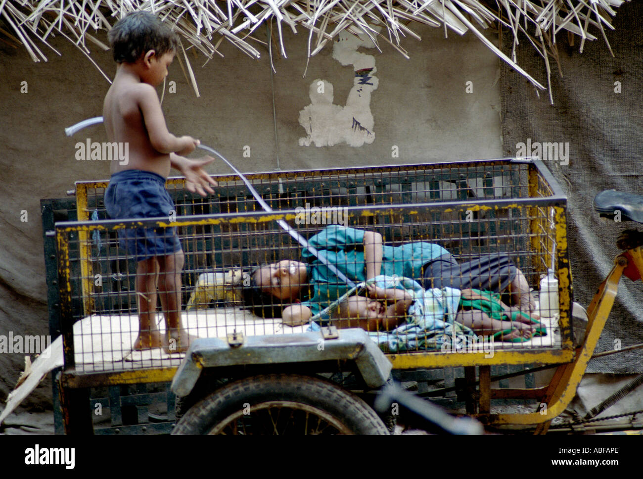 Ein Zigeunerjunge spielt auf einem Wagen als seine kranke Mutter und Bruder Schlaf Chennai Tamilnadu Indien Stockfoto