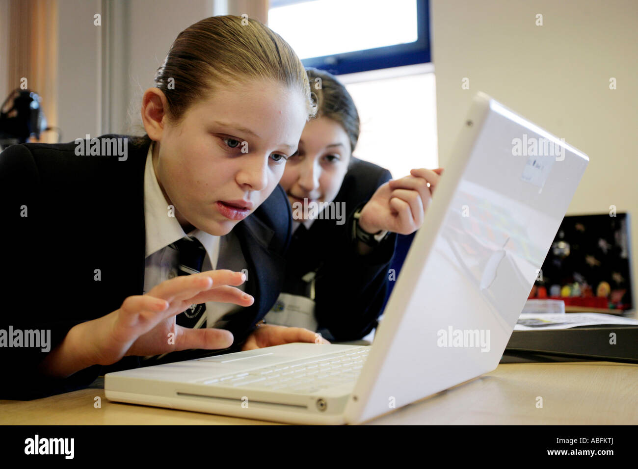 Zwei Mädchen in der Schule mit einem Apple iBook-Laptop-Computer in einem Klassenzimmer im Vereinigten Königreich Stockfoto