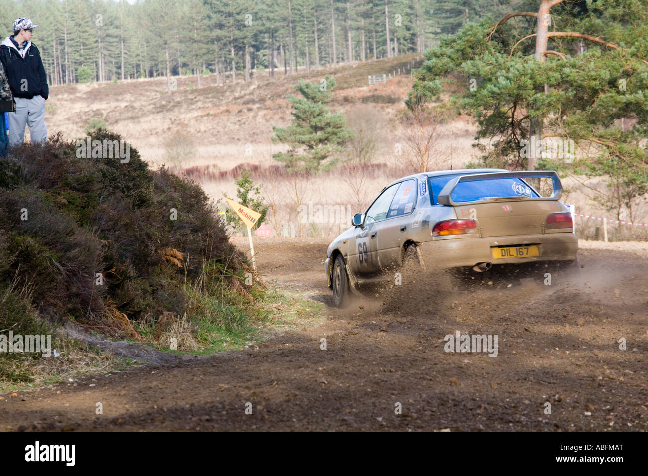 White Subaru Impreza Rallyeauto fahren Aktion Spritzwasser durch Pfütze Kies Steinen Schmutz und Schlamm zu sprühen, wie sich herausstellt eine Ecke Stockfoto