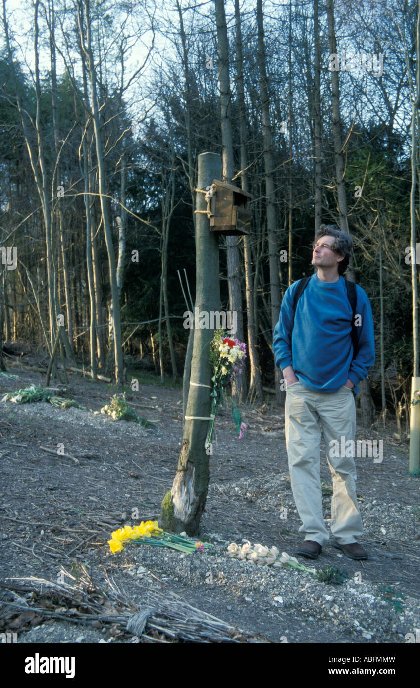 Mann mittleren Alters im grünen Gräberfeld blickte zu Denkmal ist ein Baum mit Vogel-Kasten Stockfoto