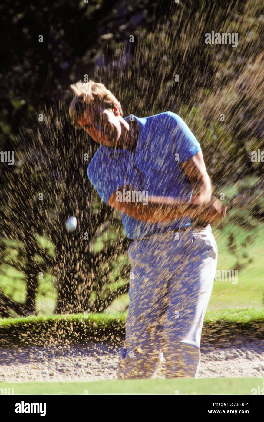 Ein männlichen Golfer Blasten aus einem Sandtrap an einem sonnigen Tag Stockfoto