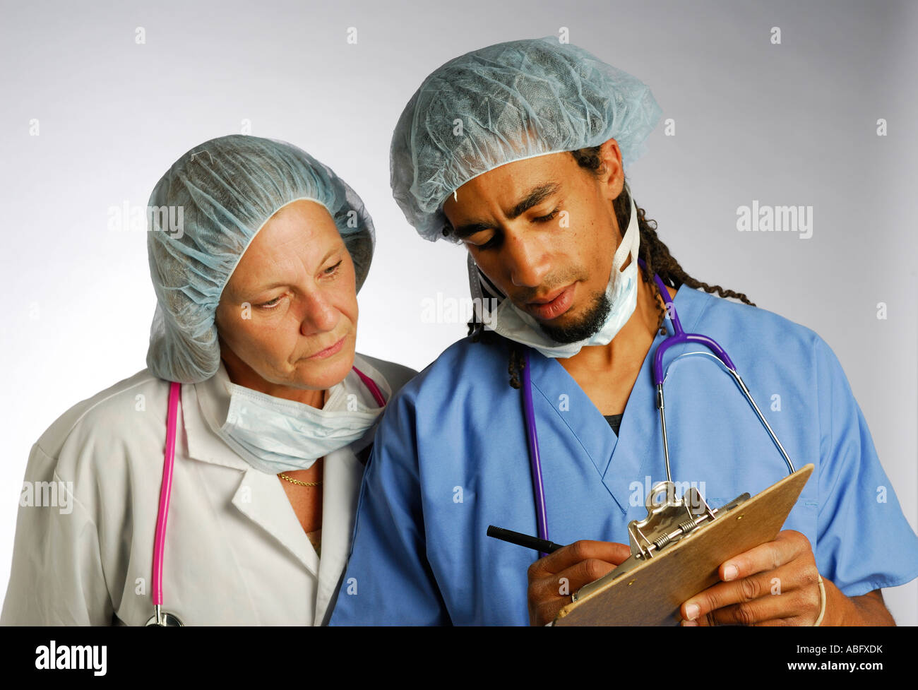 Junge schwarze Arzt mit Clip Board consulting Leitende Ärztin im Haarnetz mit Maske entfernt Stockfoto