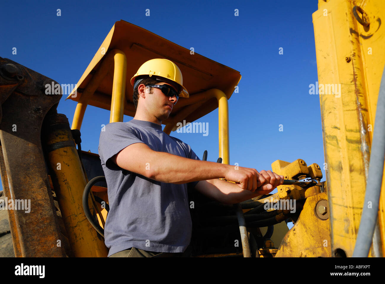 Bauarbeiter in gelben Bauhelm anziehen eine Verbindung auf einem Baggerlader Ausrüstung Stockfoto