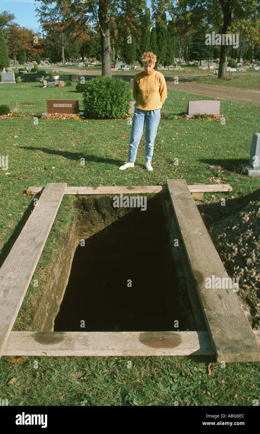 Erwachsenes Weibchen liegt bei einer offenen Grab auf einem Friedhof Stockfoto