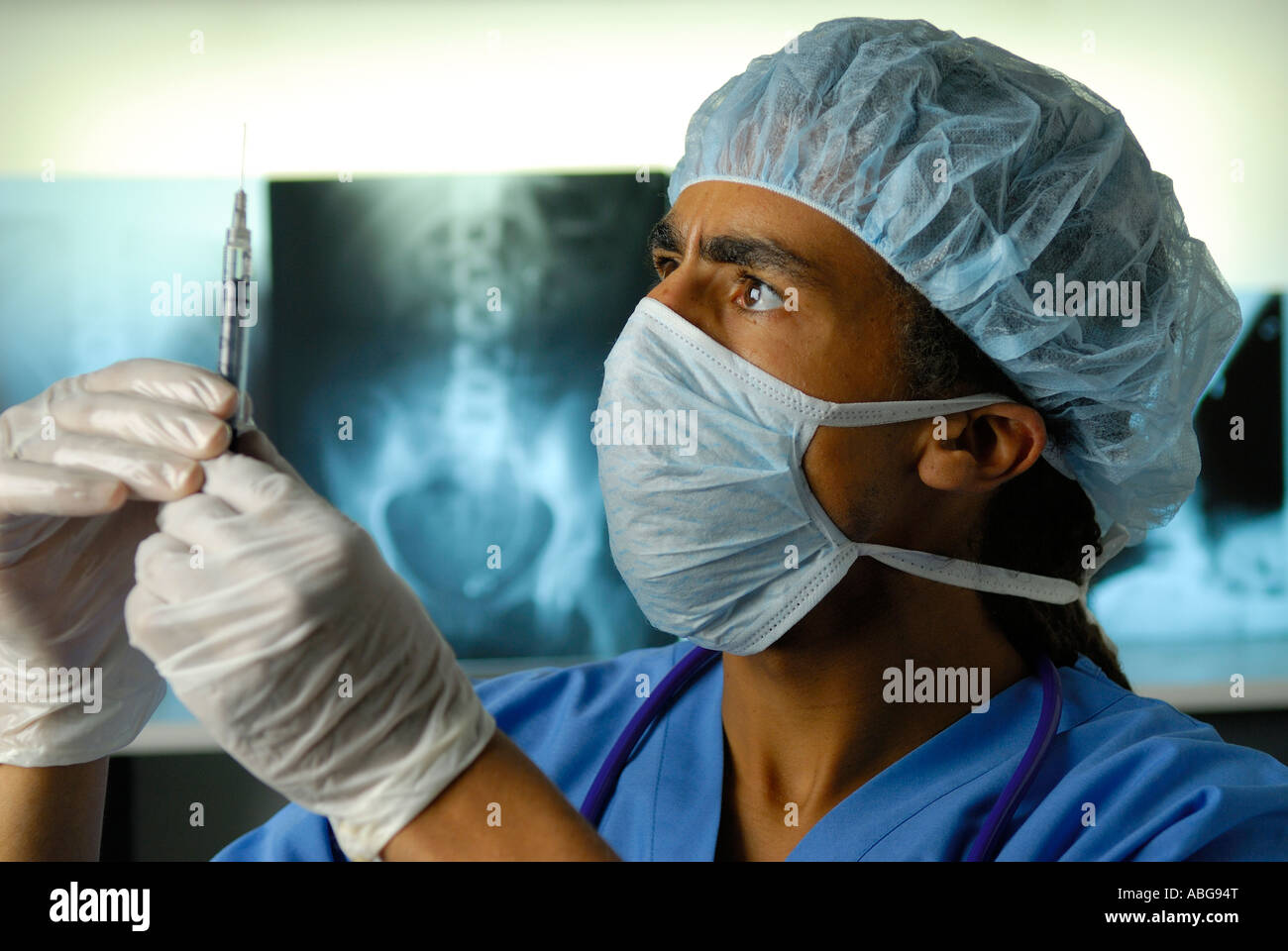 Arzt in Maske und Harnet Vorbereitung Spritze für die Injektion neben Xray Film Folien Stockfoto