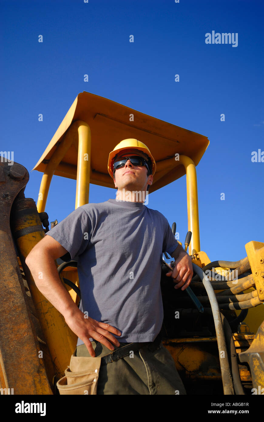 Bauarbeiter mit harten Hut und Werkzeug Gürtel stehen maschinell Baggerlader Stockfoto