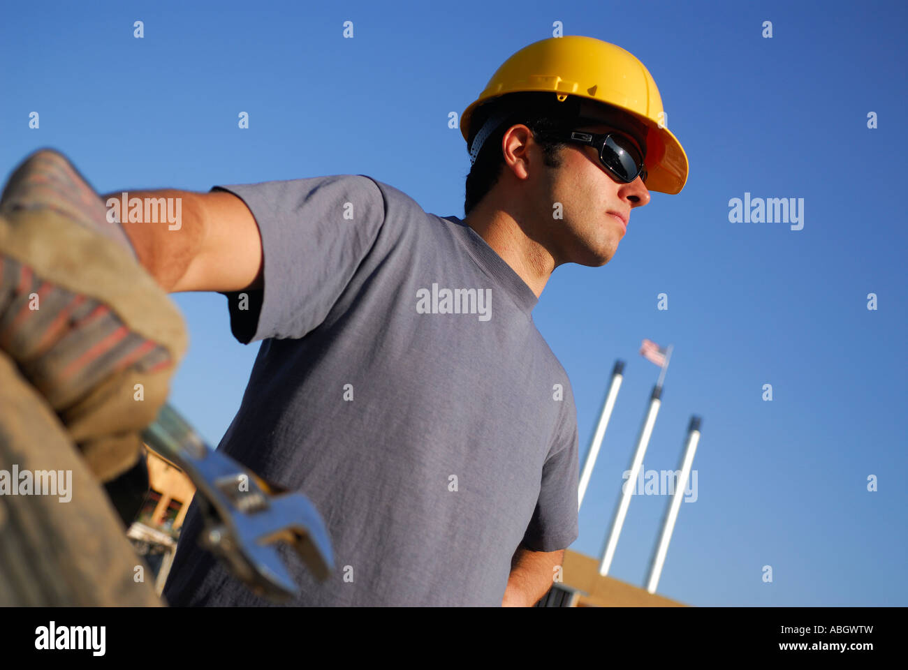 Junge männliche Bauarbeiter mit Schutzhelm und Arbeitshandschuhe mit Schraubenschlüssel mit blauem Himmel Bend Oregon anhalten Stockfoto