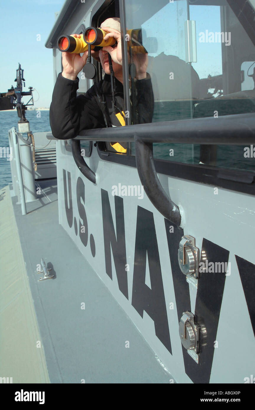 US Marine Bootsmann Mate schaut durch ein Fernglas wie er patrouilliert in küstennahen Gewässern des Persischen Golfs Stockfoto