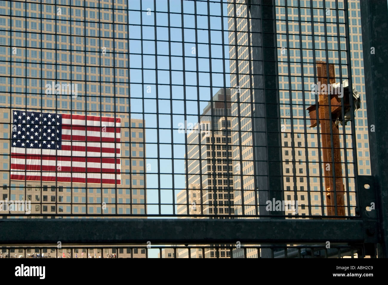 Ein Blick durch ein Gitter Zaun eines großen verrostet Kreuz gemacht von Trägern aus der zerstörten Zwillingstürme und eine große amerikanische Flagge-Witz Stockfoto