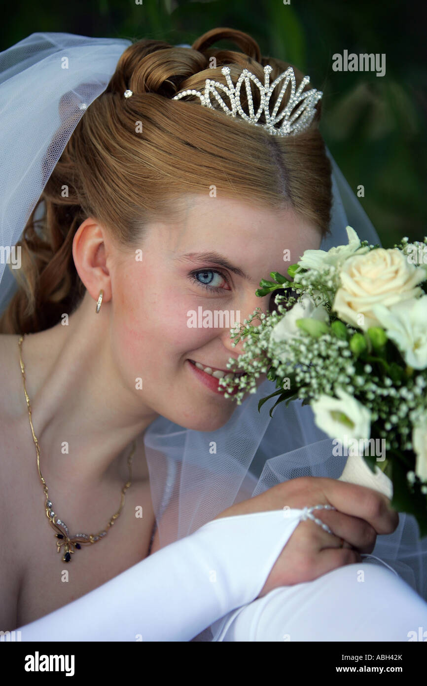Ein Porträt einer Braut in eine traditionelle weiße Hochzeit Kleid abgebildet hier lächelnd und Blumenstrauß zu halten. Stockfoto