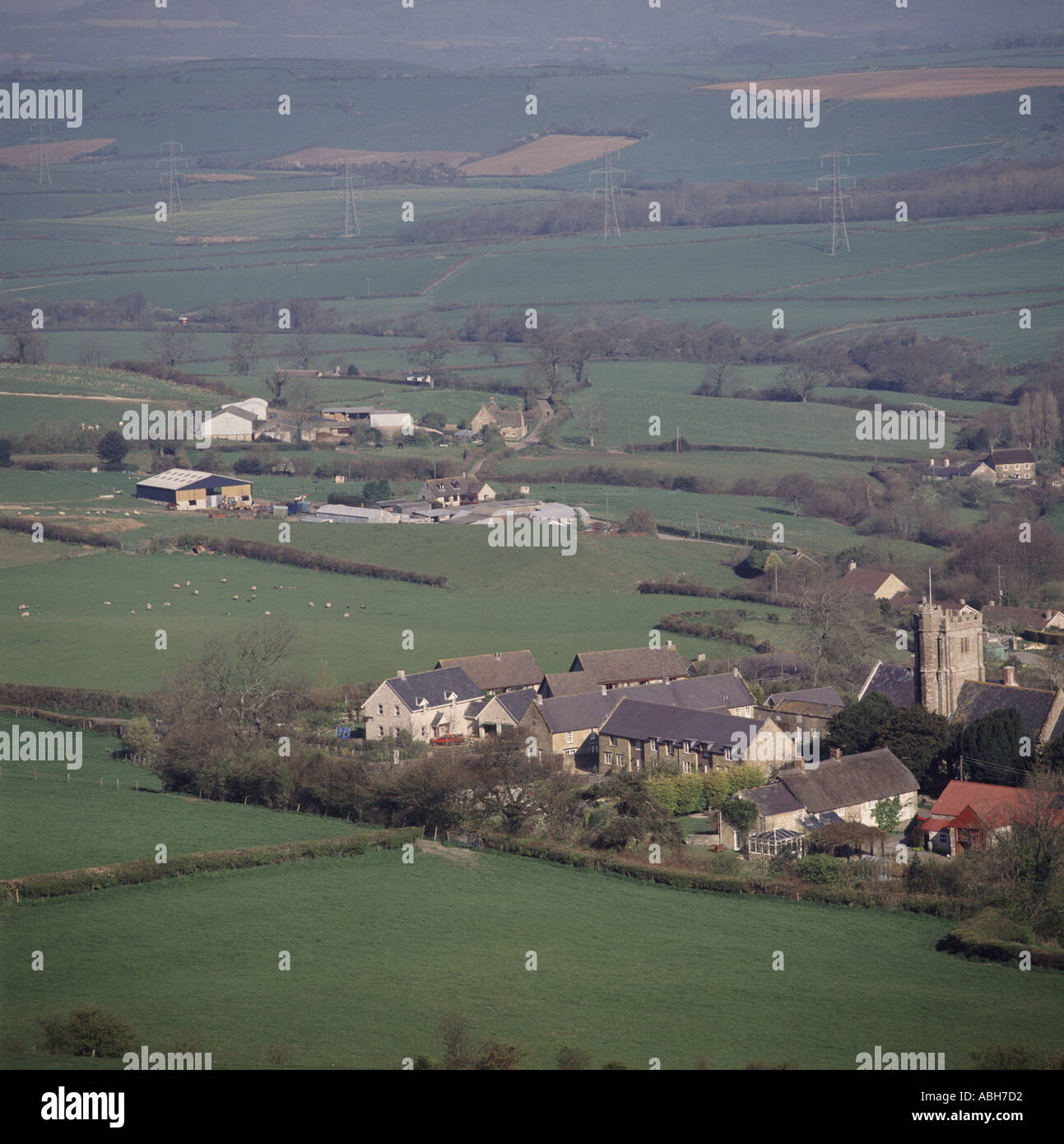Blick hinunter auf, kleines Dorf mit Kirche und alte und neue Gehäuse eingestellt in Ackerland in der Nähe von Dorchester, Dorset Stockfoto