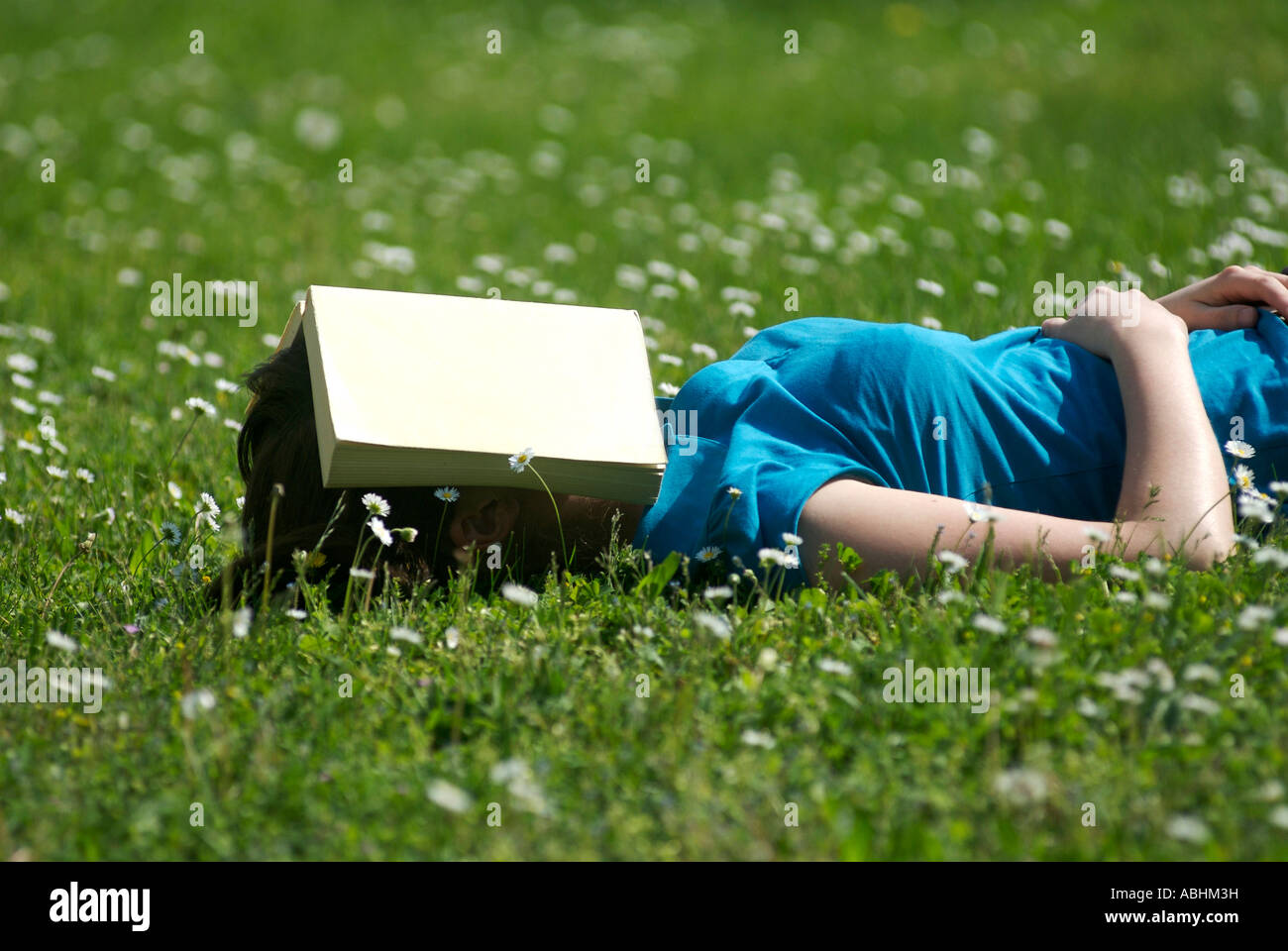 Schüler lesen / schlafen im Park / Garten mit einem Buch über das Gesicht Stockfoto