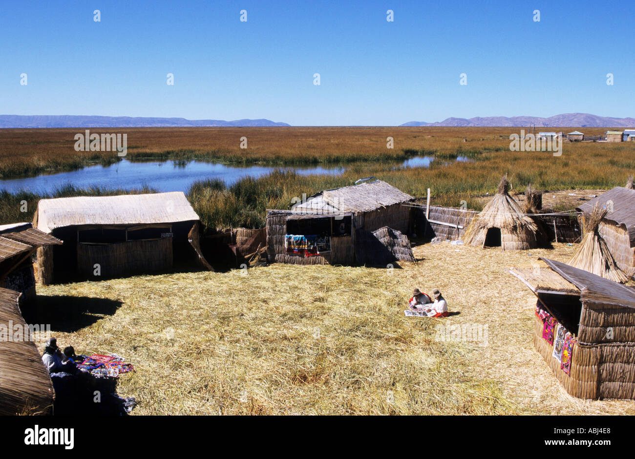 Titicacasee, Peru. Typische Häuser aus Schilf auf der schwimmenden Insel der Uros mit Frauen in traditioneller Tracht. Stockfoto