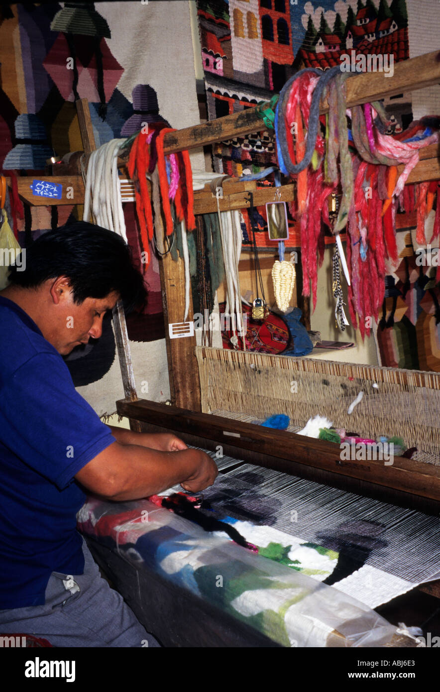 Ollantaytambo, Peru. Mann mit einem traditionellen Webstuhl um eine dekorative Tapisserie an Touristen verkaufen. Stockfoto