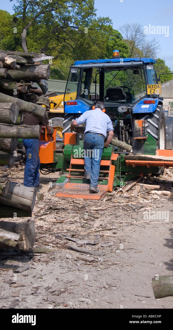 Forstwirtschaft Arbeiter Mann teilen Holz auf einen Traktor montiert Splitter, Protokolle zu machen. Stockfoto