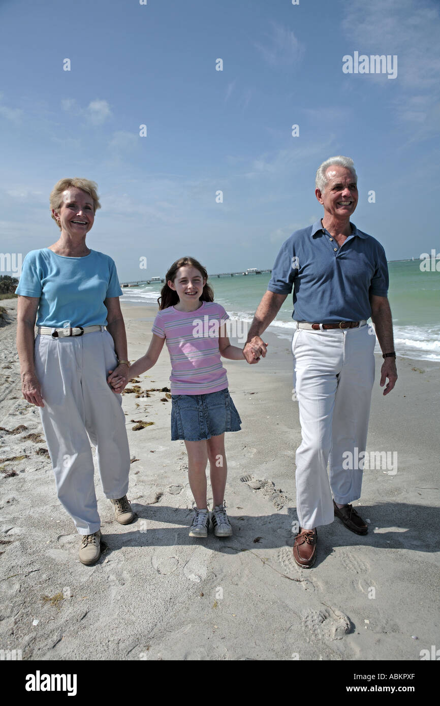 Foto von pensionierten älteres Paar mit ihrer Enkelin Händchenhalten und weißen Sandstrand am Meer schlendern Stockfoto