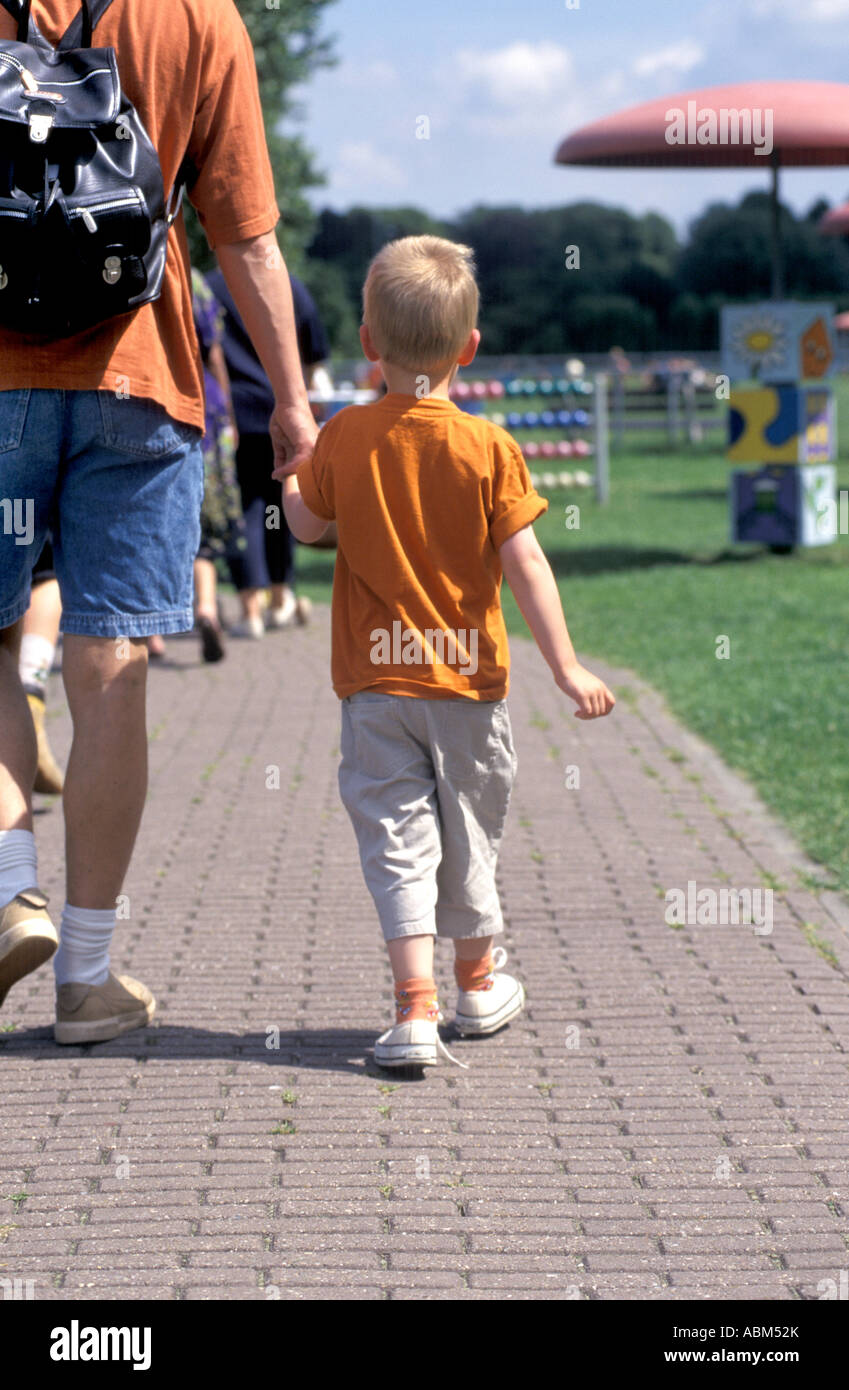 Kleinen Jungen zu Fuß auf die Hand seines Vaters Stockfoto
