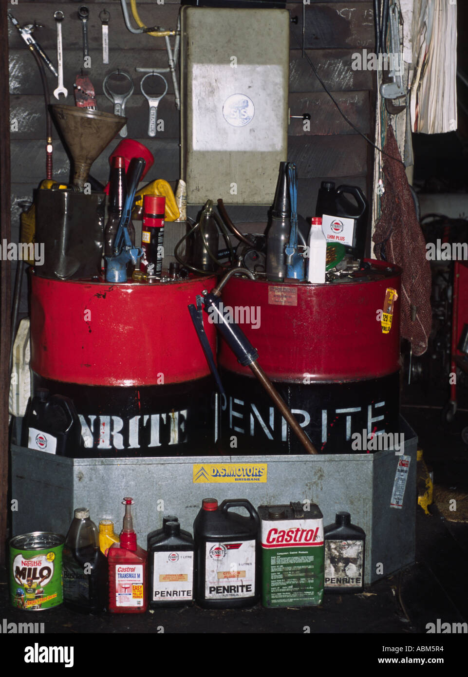 Öl-Trommeln dominieren die Szenerie in ein Mechaniker unaufgeräumten Werkstatt Stockfoto