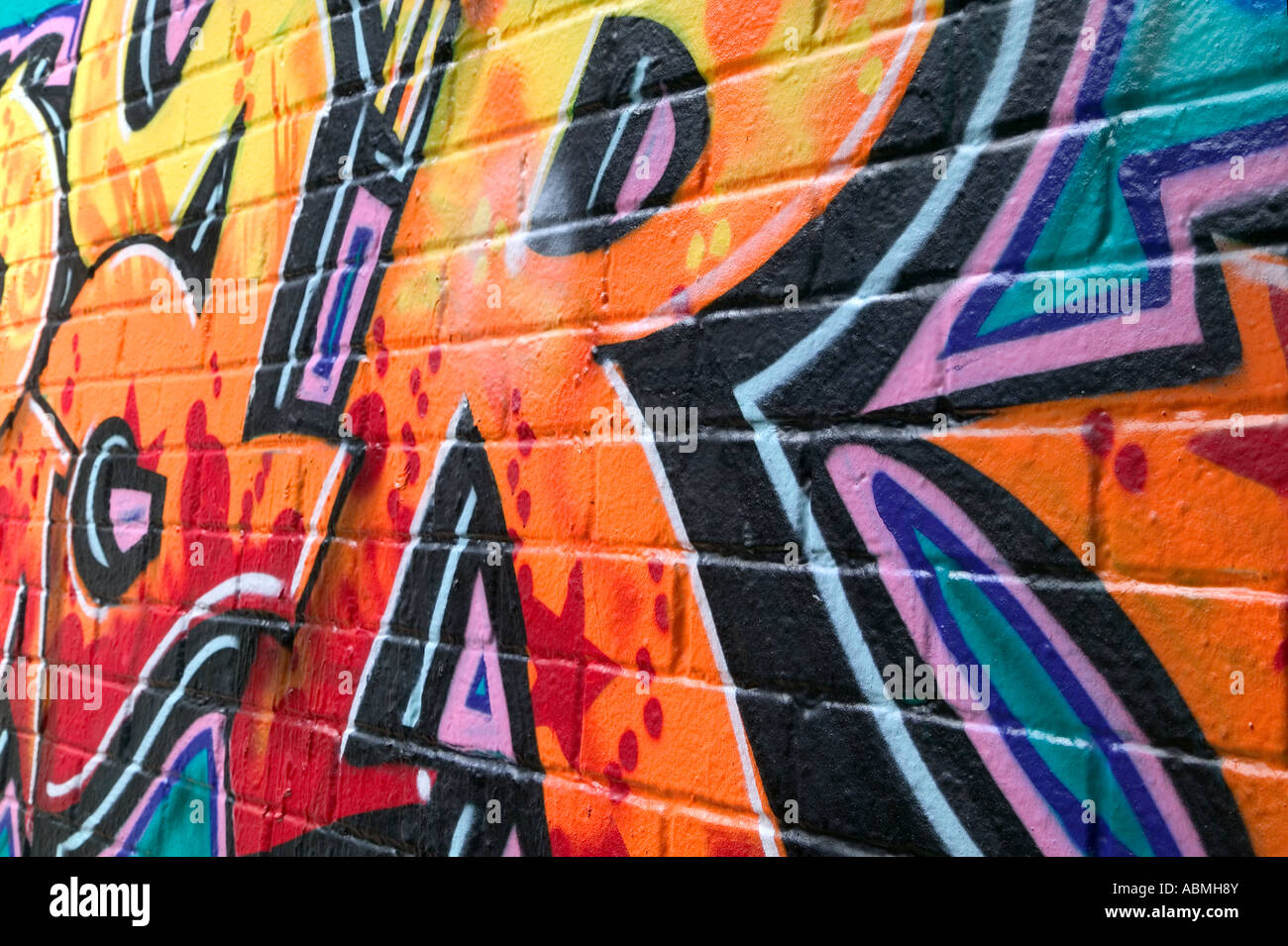 Ziegelmauer bedeckt in Graffiti-Seitenansicht Stockfoto