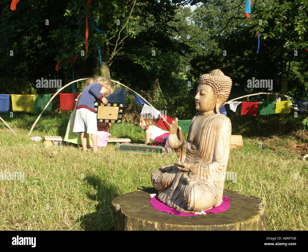 eine hölzerne Buddha sitzt auf Baumstumpf beim Buddhafields Festival uk 2005 Stockfoto
