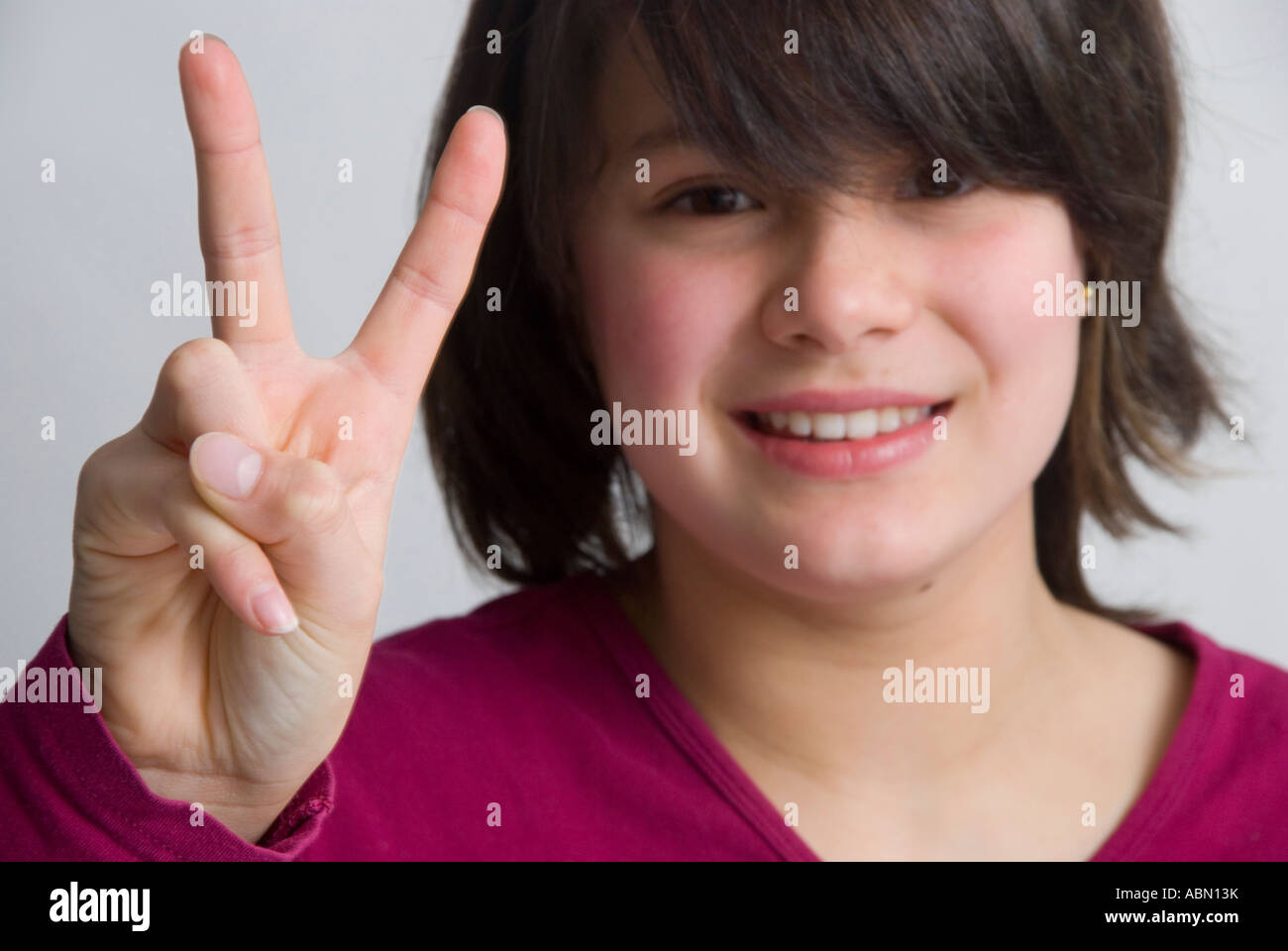 Das junge 11-jährige Mädchen, das das V für das Siegeszeichen gibt, wird auch Friedenszeichen genannt Stockfoto