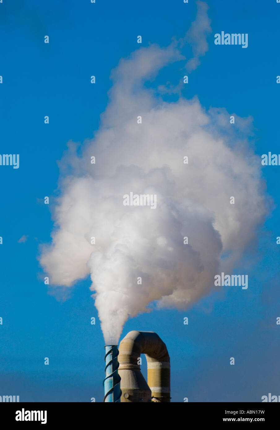 Ein Schornstein strahlt eine Wolke von industriellen Emissionen vor einem strahlend blauen Himmel Stockfoto