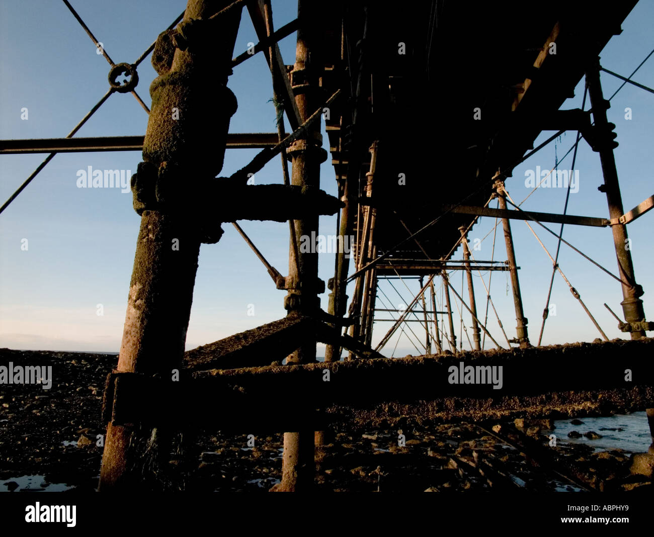 Unter Aberystwyth Pier auf der Suche nach oben durch das rostige Eisen Beine und streben bei Ebbe an einem Sommertag am Abend Stockfoto