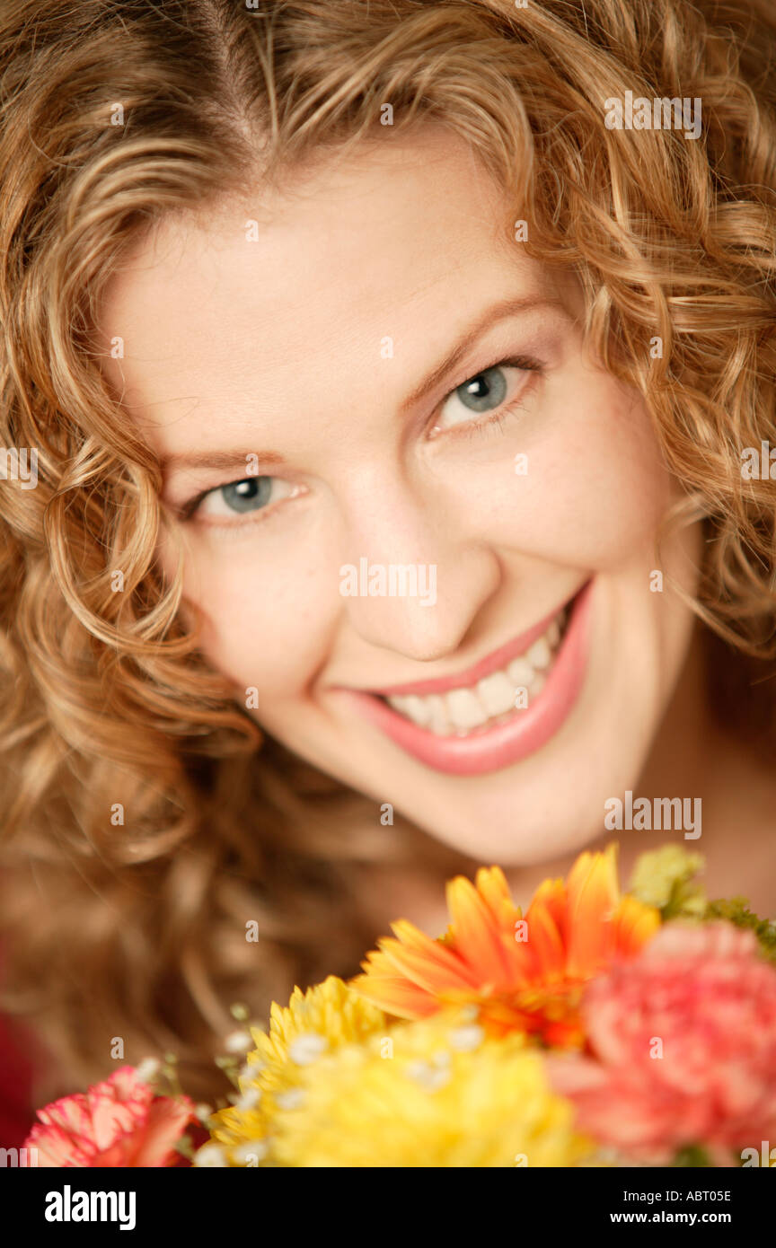 Junge Frau lächelt in die Kamera mit Blumen Stockfoto