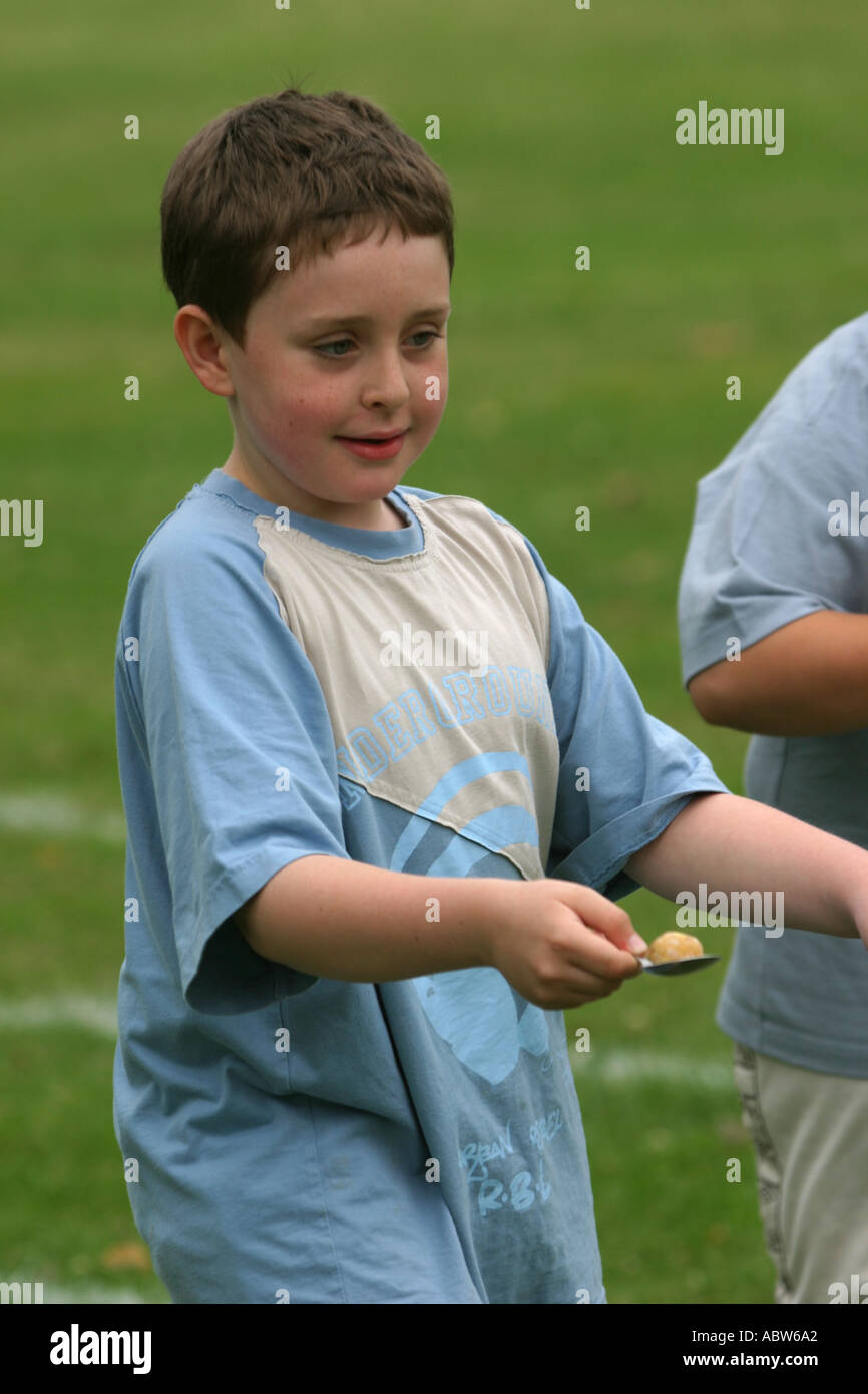 Junior Schuljunge ein Ei und Löffel Rennen an seiner Schule Sport Tag, Clissold Park, London, UK. Stockfoto