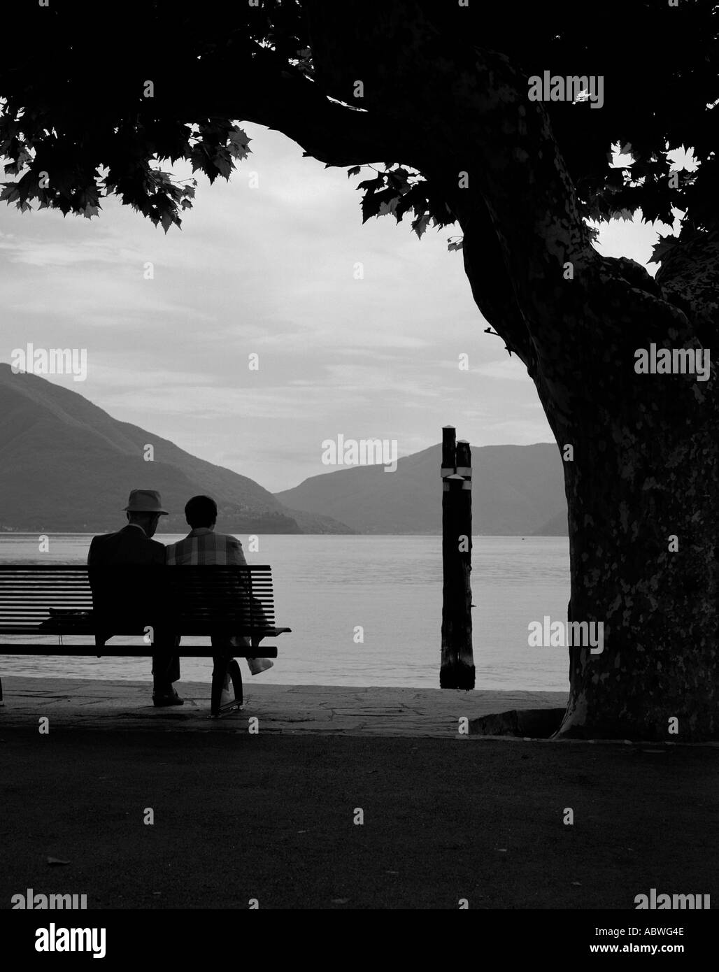 Das Paar sitzt alleine auf einer Bank mit Blick auf den See Stockfoto