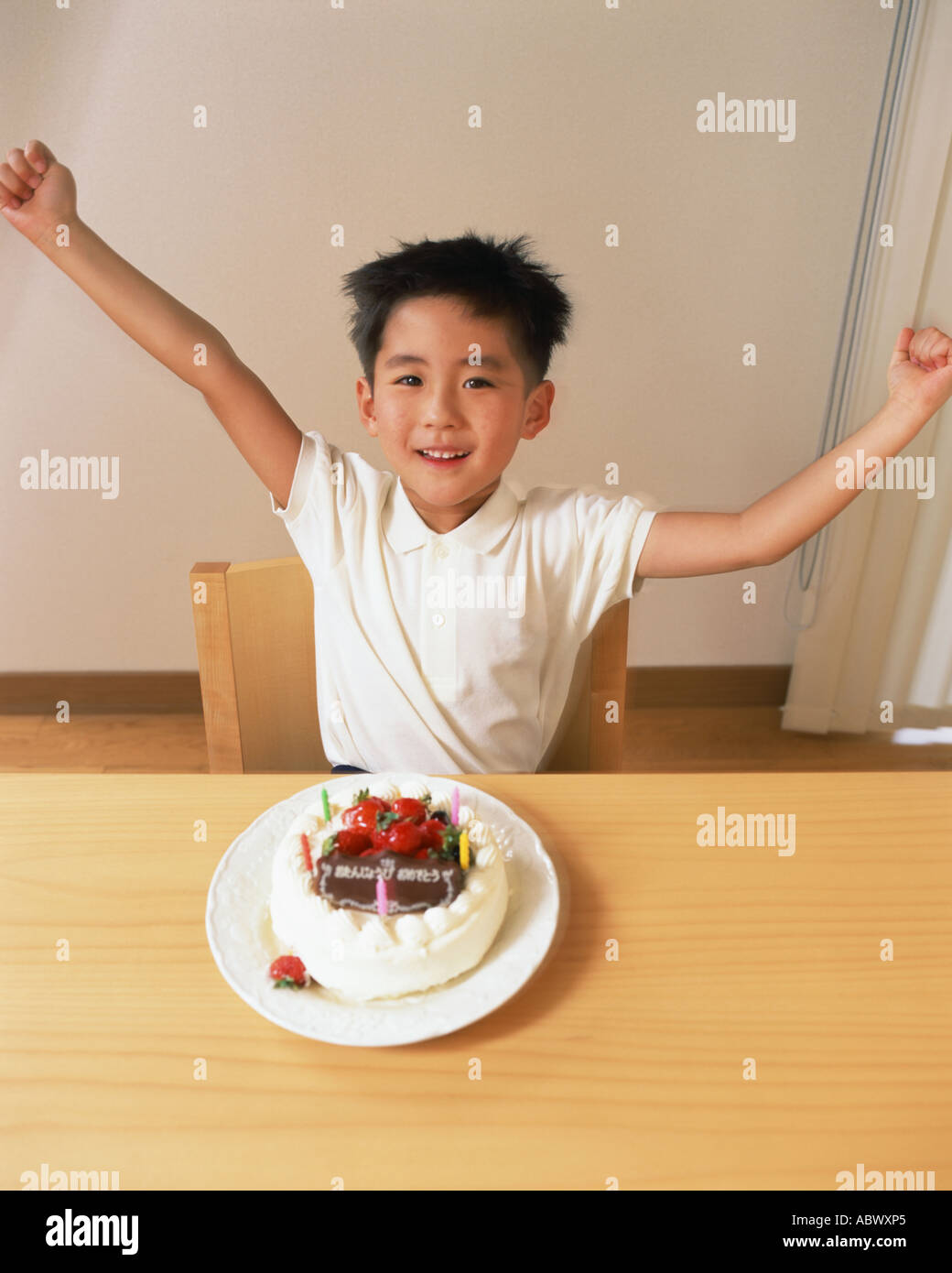 Ein kleiner Junge, der seine Arme in Aufregung an seinem Geburtstag Stockfoto