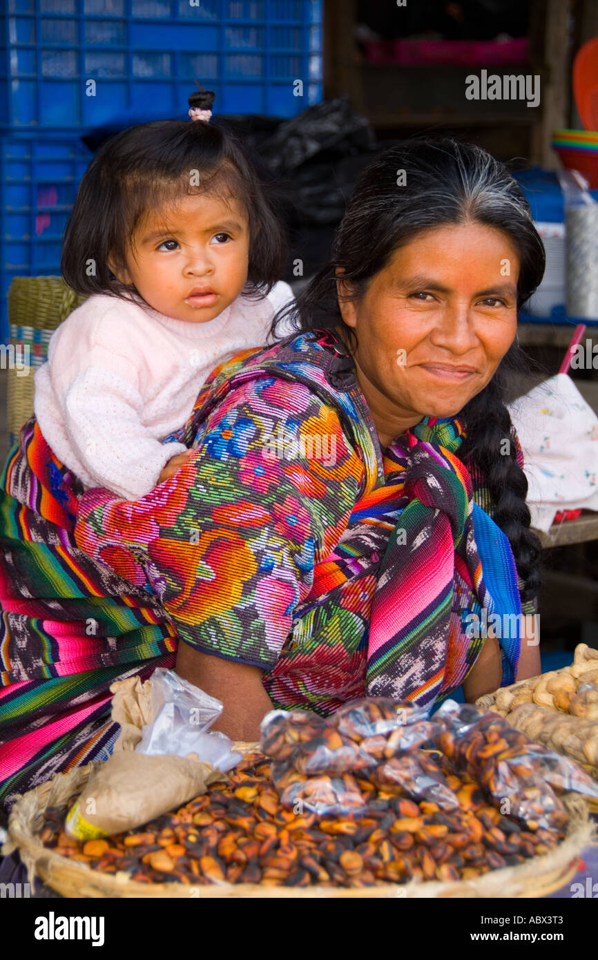 Bunte Frau mit Enkelin auf Rückseite im Markt in touristischen Dorf von Antigua Guatemala Stockfoto