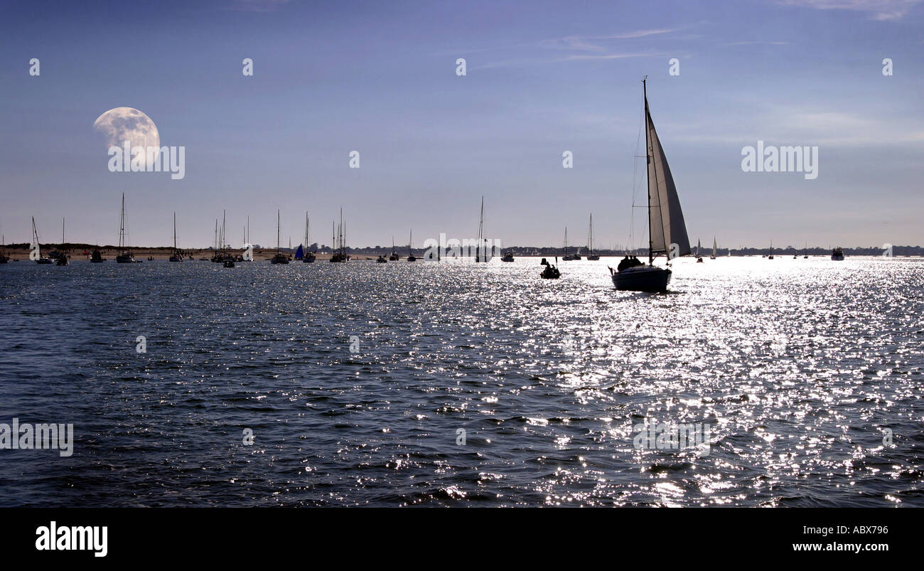 Yacht segeln bei Sonnenuntergang mit aufgehenden Mond, Osten Kopf, Chichester, Sussex, UK, als ein Konzept Bild für Freiheit, Dämmerung, Ende der Tage Stockfoto
