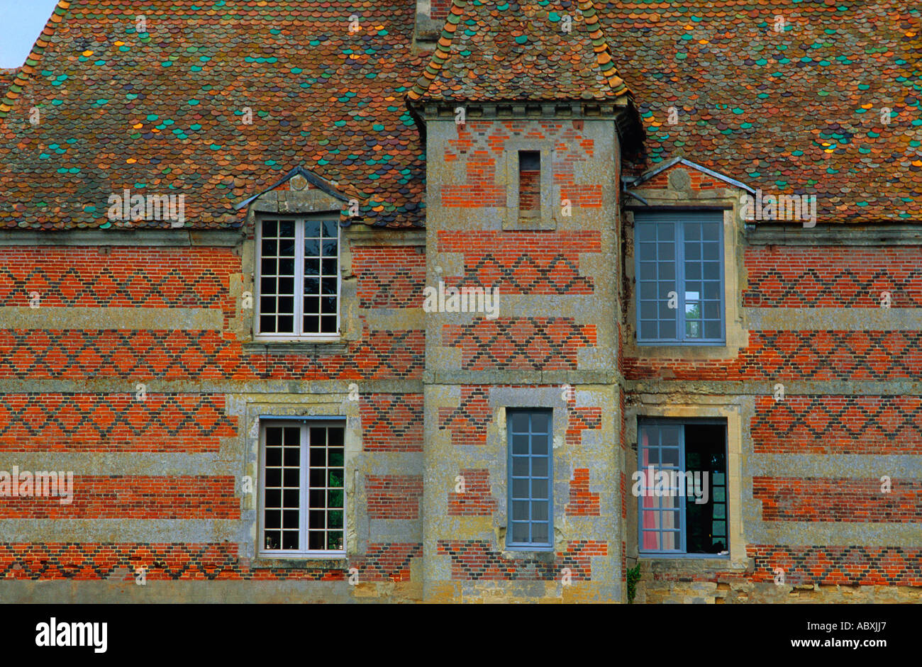 Frankreich Normandie Französisches Provinzhaus. Gemusterte Backstein- und Steinfassade eines Landhauses mit mehrfarbigem Schieferdach und Gitterfenstern Stockfoto