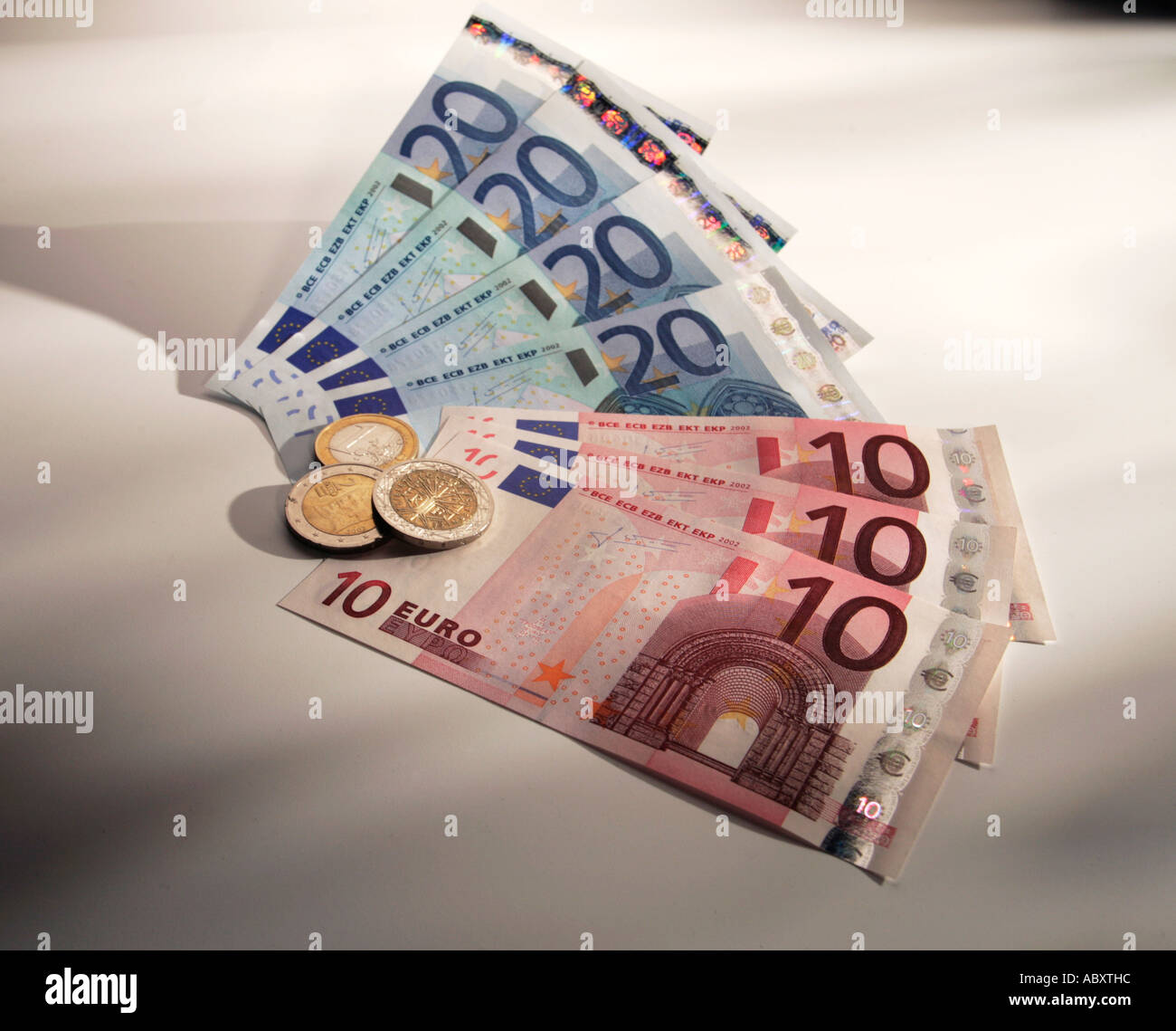 Fan von 10 & 20 Euro Banknoten & 1 Euro-Münzen mit Schatten & bunten Hintergrund Stockfoto