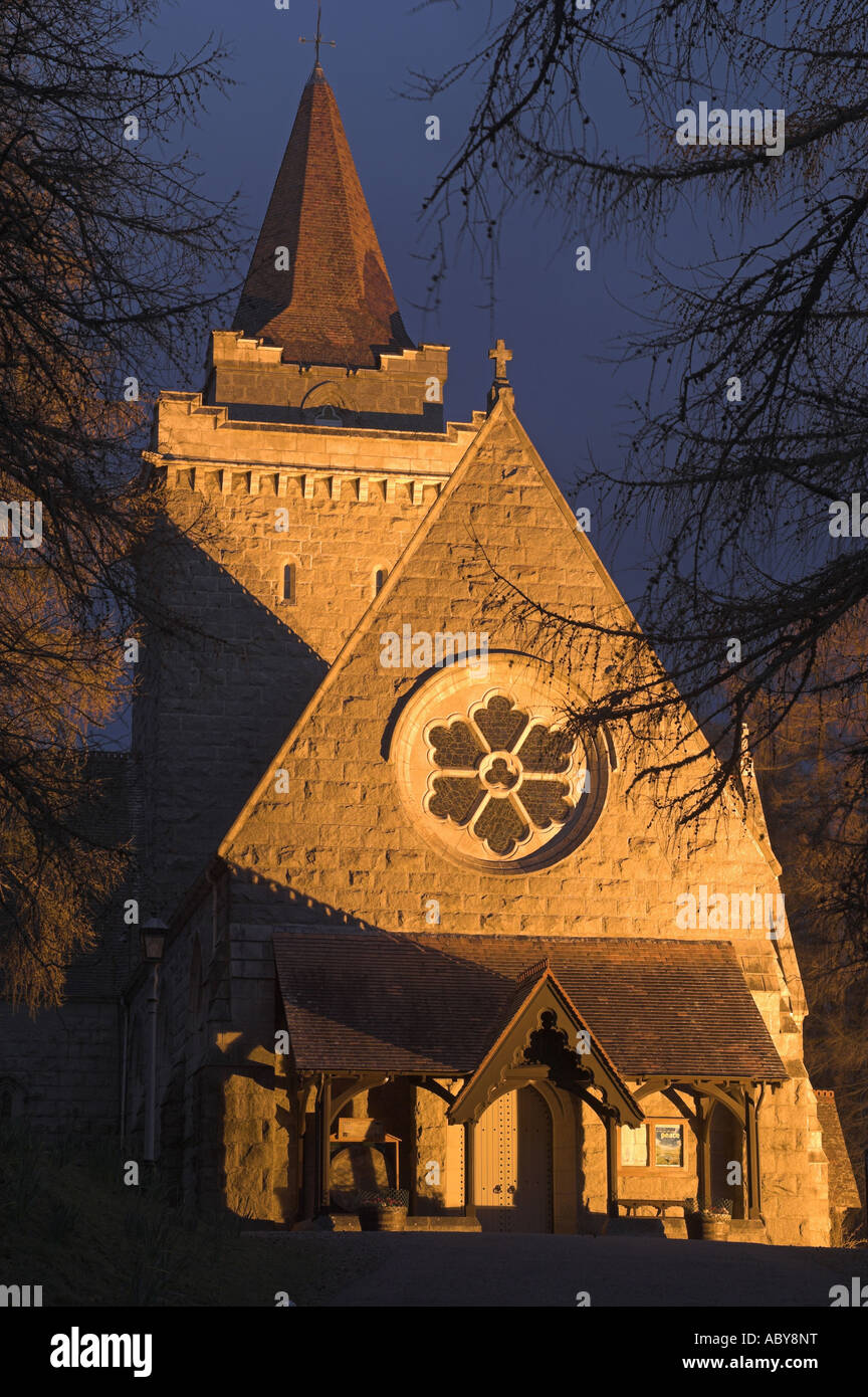 Crathie Kirche in der Nähe von Balmoral Castle in Royal Deeside, Aberdeenshire, mit Flutlicht in der Abenddämmerung in einem Hain der Lärchen. Stockfoto