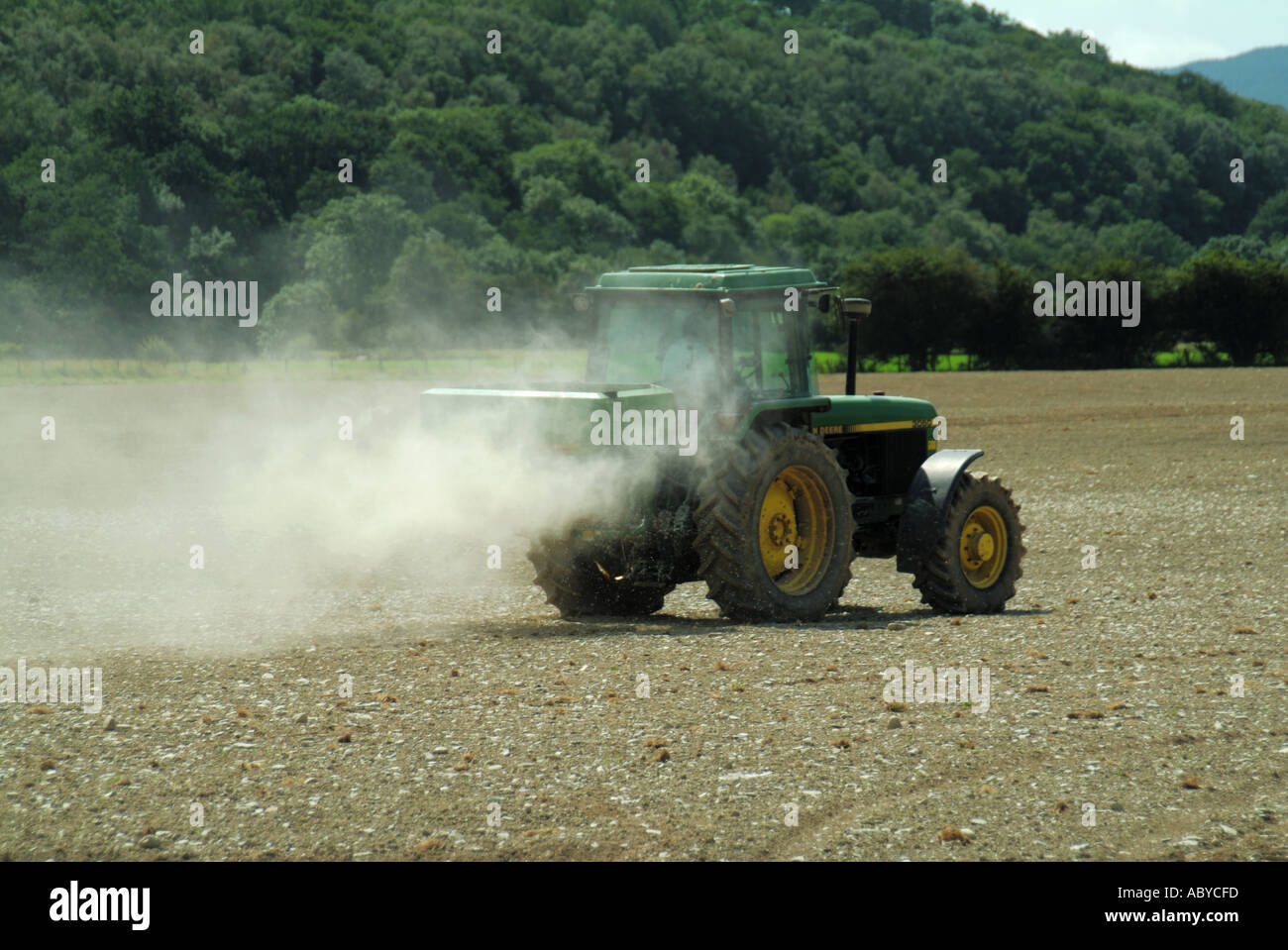 Landwirt treibende John Deere Traktor mit Streuer Anlage Verbreitung staubigen landwirtschaftliche Kalk auf Feld-Hof in der Nähe von Machynlleth Powys in Wales Großbritannien Landwirtschaft Stockfoto