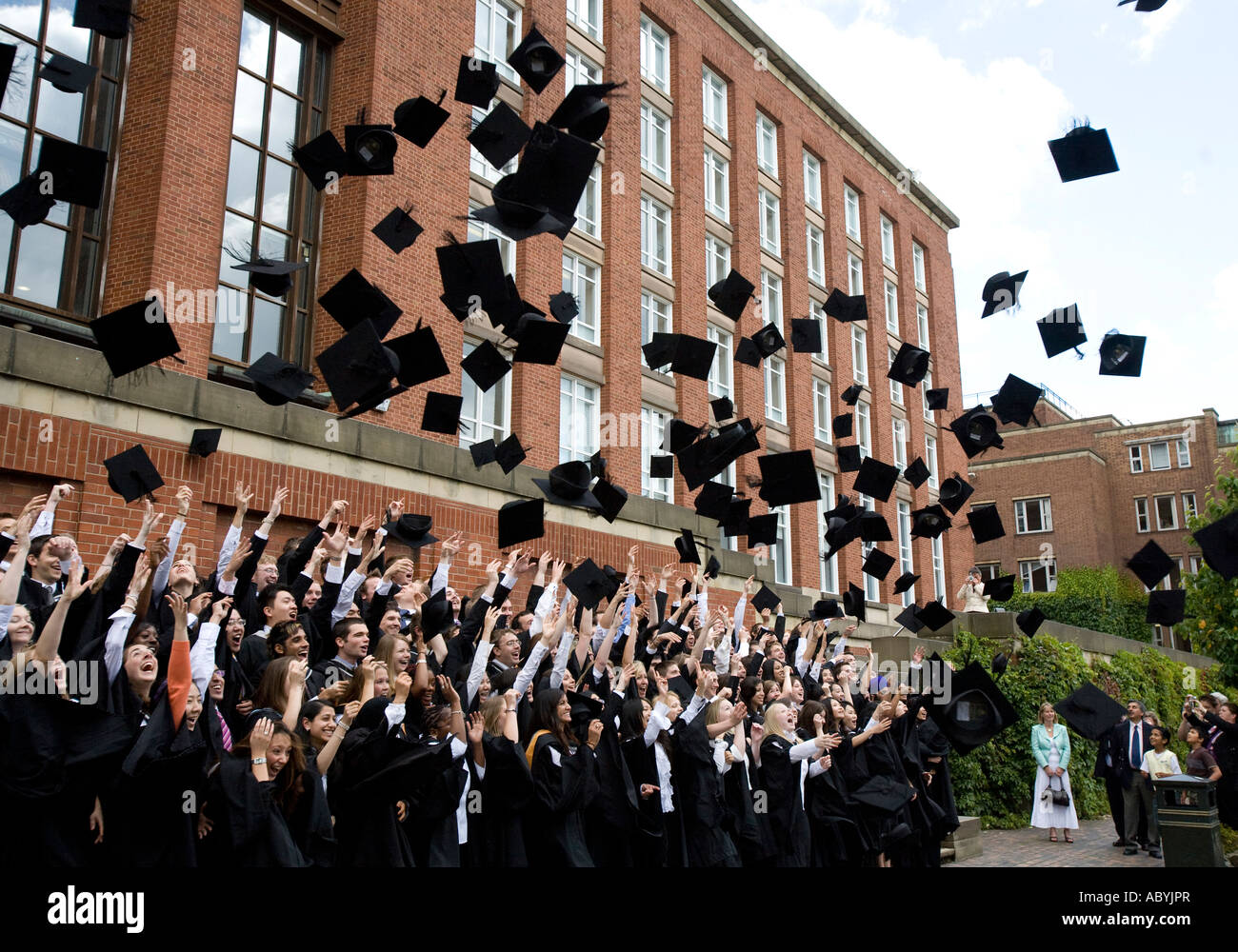 Absolventinnen und Absolventen werfen ihre Mörtel-Boards in der Luft an der Graduierung Tag, Universität von Birmingham, England, UK. Stockfoto