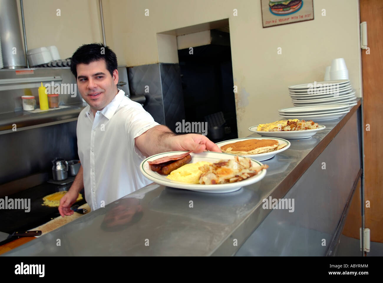 Kurzer Koch bereitet Essen in einem kleinen restaurant Stockfoto