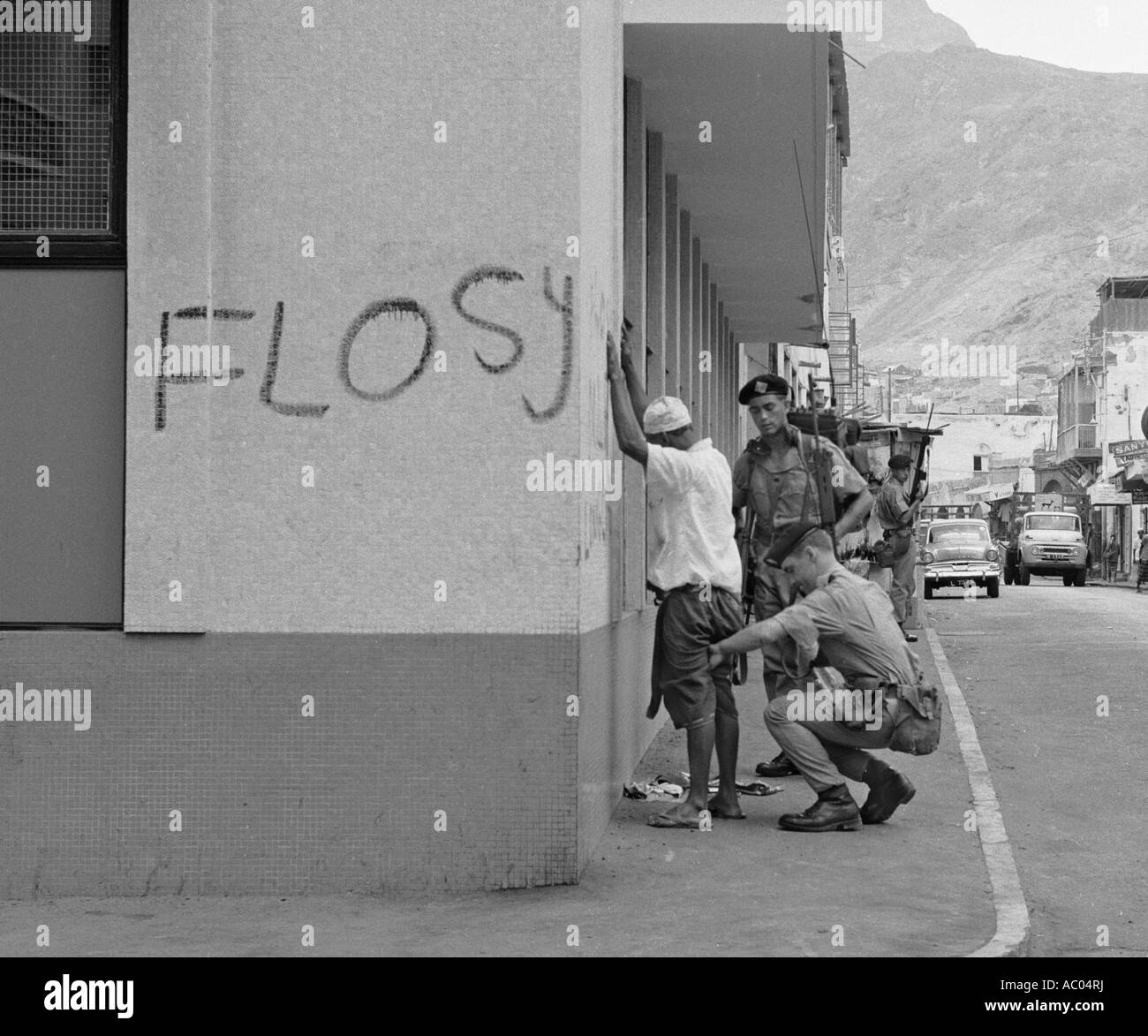 Suche ein Araber in Aden in1966 Soldaten. FLOSY The Front für die Befreiung von South Yemen Slogan beschmiert an Wand des Gebäudes Stockfoto