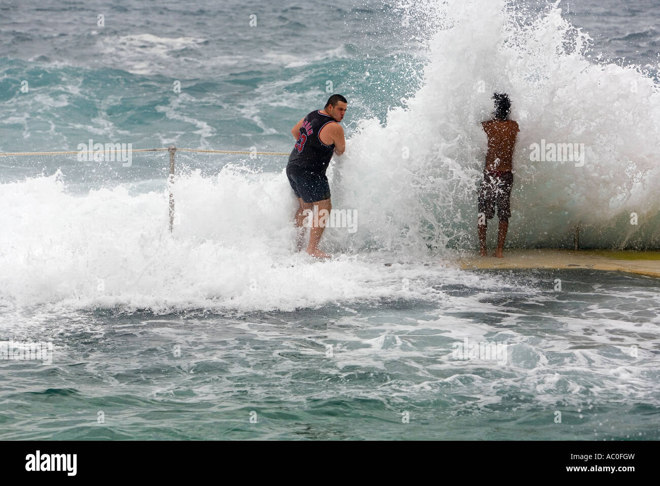 Schwimmer sind von Wellen, die über den Rand der Bronte Bäder an den östlichen Stränden Sydneys überschwemmt. Stockfoto