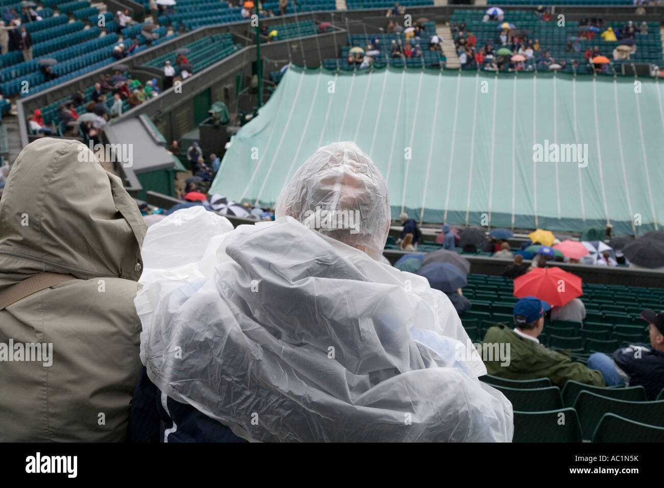 Center Court Regen Störung und Zuschauer im Regenschutz im Wimbledon Tennis Championship UK Stockfoto
