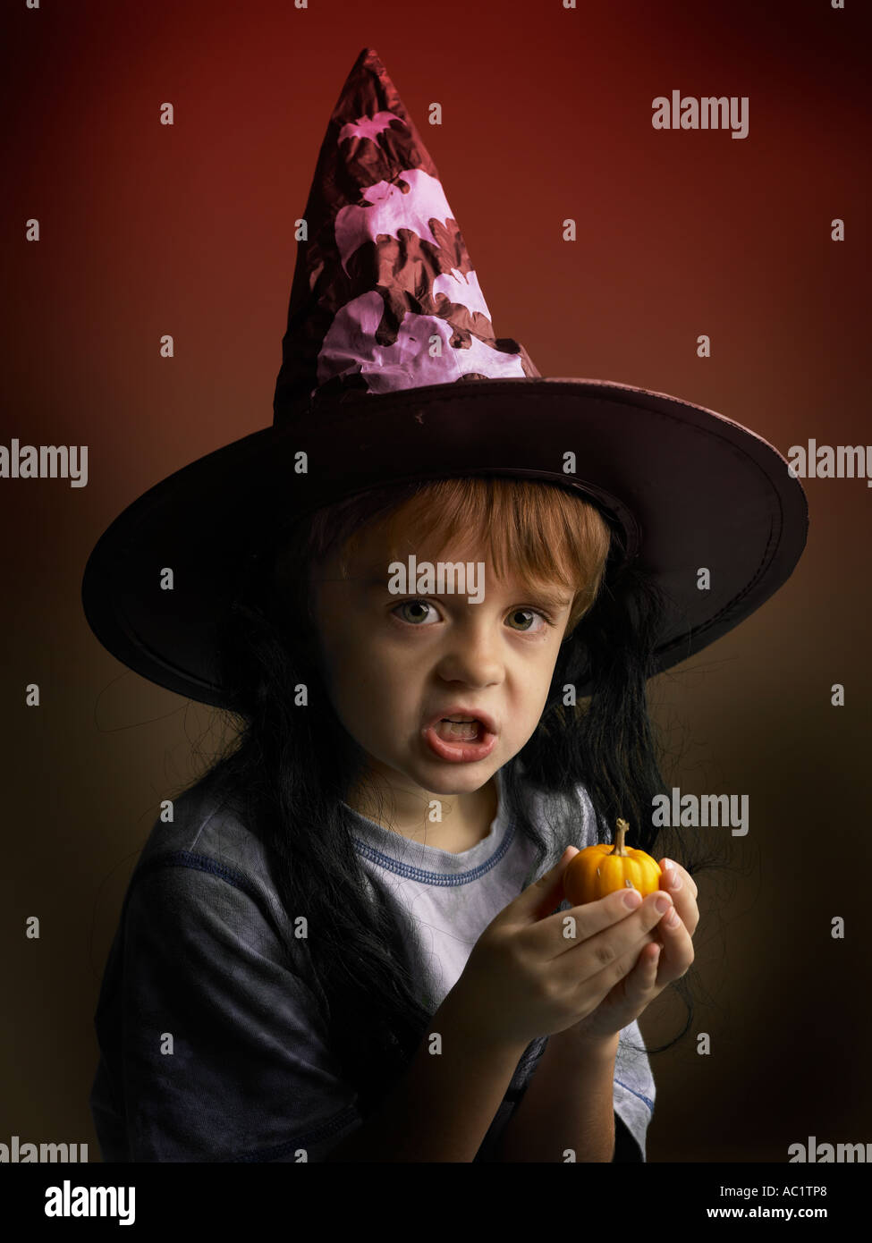 Junge an Halloween Hexen Hut hält kleine Kürbis Stockfoto