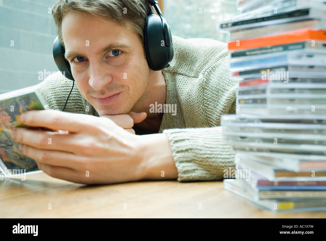 Mann mit Kopfhörer, CD-Cover in den Händen halten Stockfoto