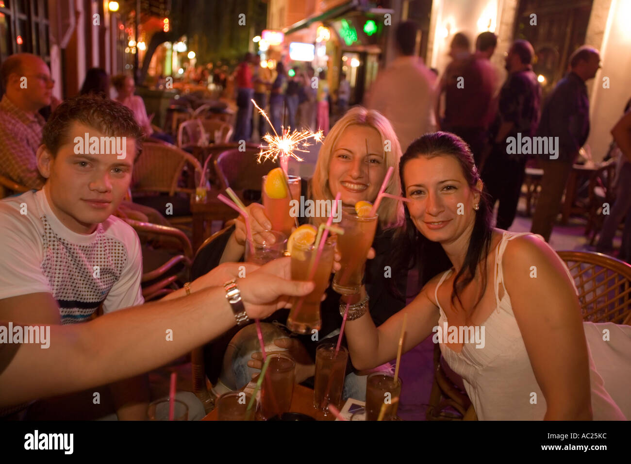 Toasten mit Jugendlichen Getränke in eine Open-Air-Bar am Abend Kos Stadt Kos Griechenland Stockfoto