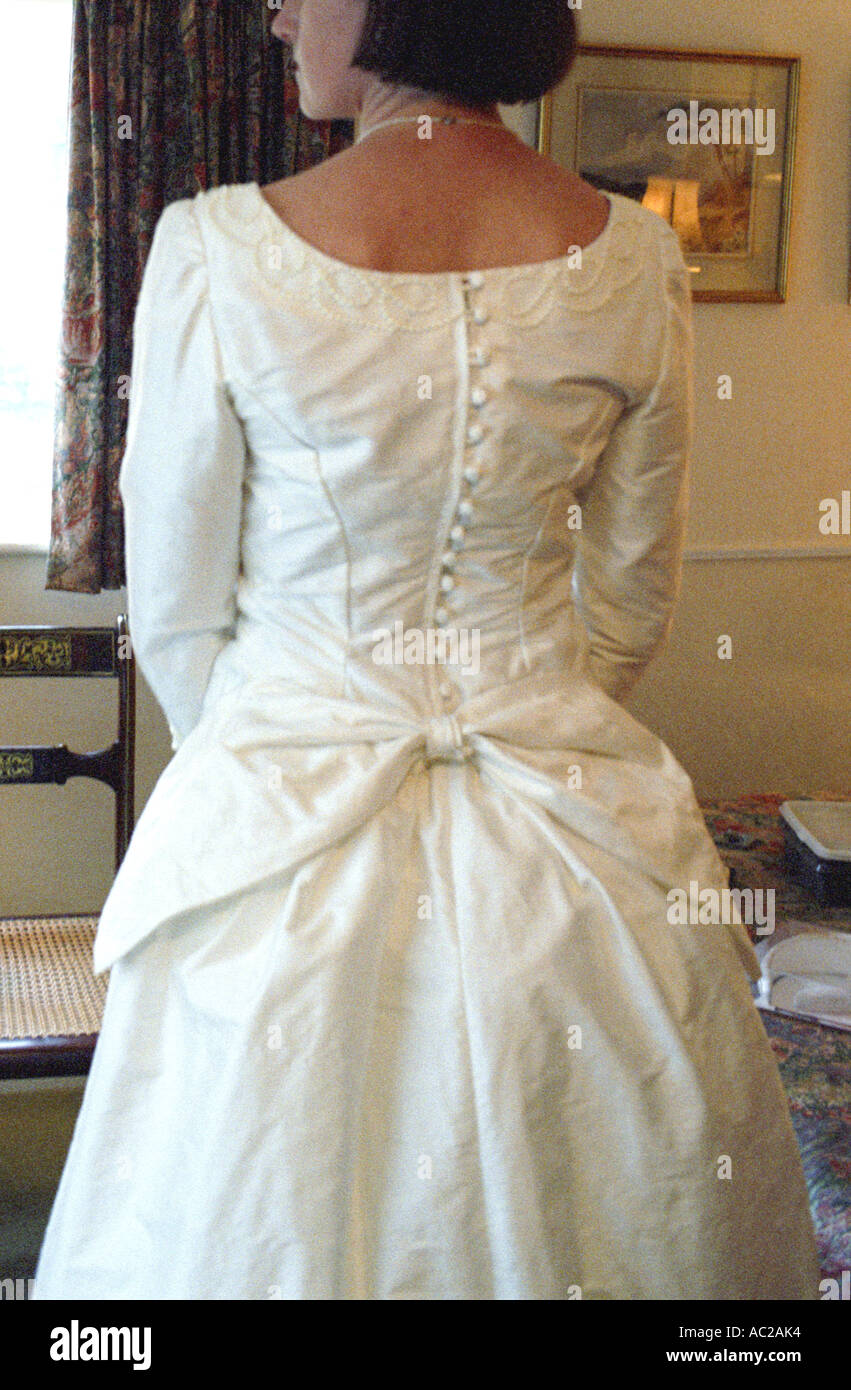 Braut in ihrem Schlafzimmer vor ihrer Hochzeit zeigen eine Schleife auf der Rückseite des Kleides Stockfoto