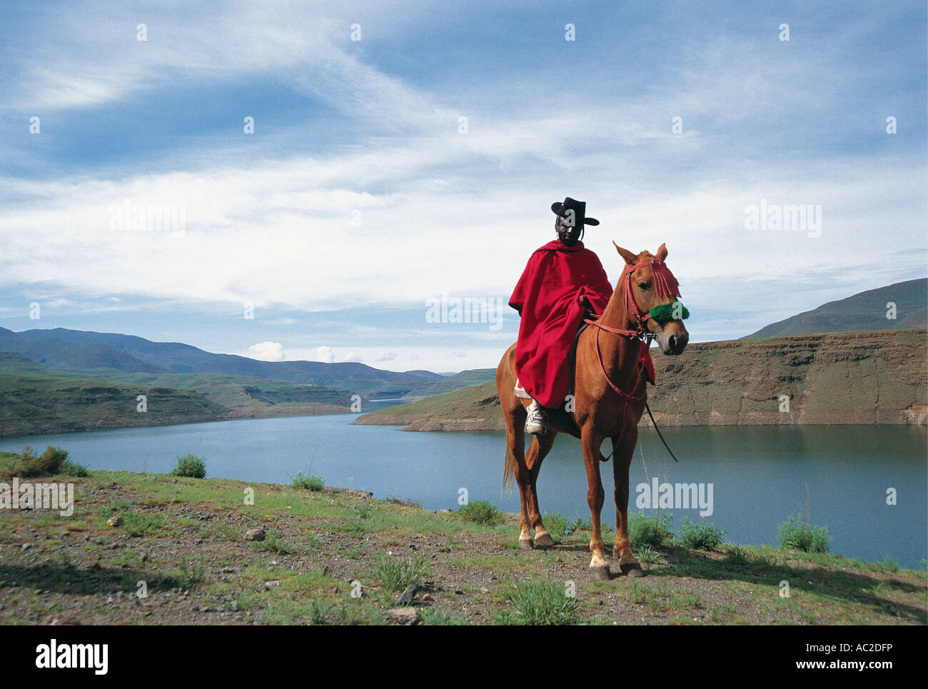 Roten getarnten schwarzen afrikanischen Mann mit schwarzen Hut auf einem Pferd im Berg Königreich von Lesotho Stockfoto