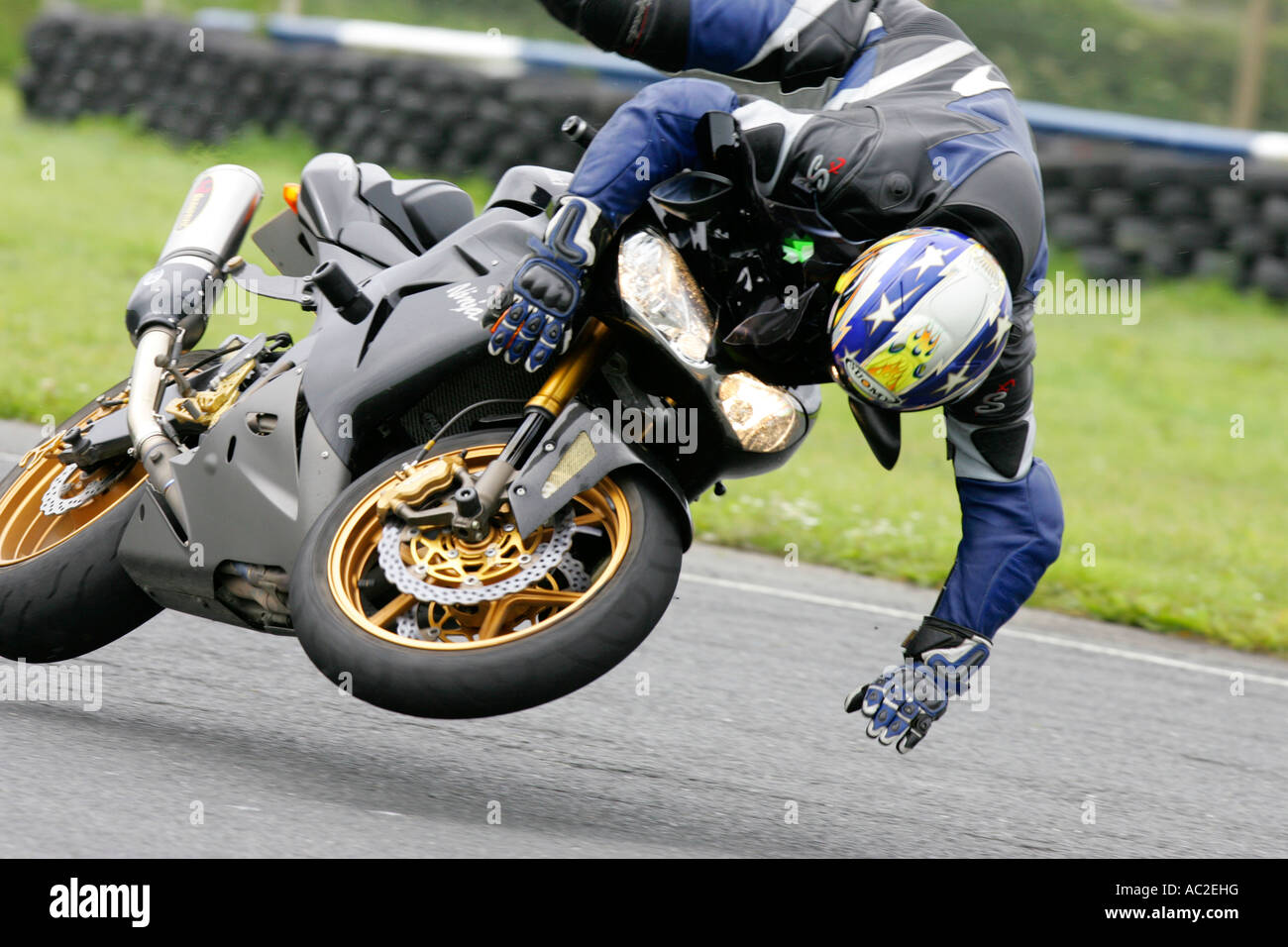 Fahrer in Leder und Helm fliegen über Lenker während Motorrad Crash trackday Stockfoto
