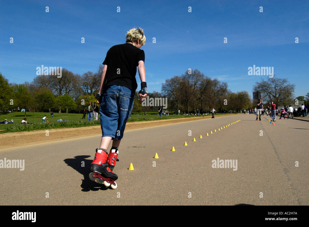 Junger Teenager Inlineskating durch Slalom Kegel im Hyde Park, London, England UK Stockfoto