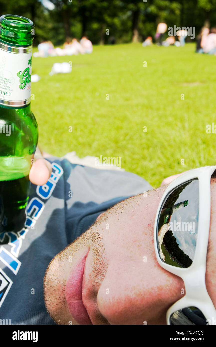 Junger Mann liegend in Park mit Flasche Bier Stockfoto